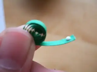 3. Then, put a little dot of glue on the end of the paper strip and press it against the side of the circle and hold it there for 5-10 seconds.