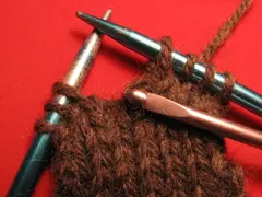 Pull the dropped stitch through the loop with the crochet hook. You might need to twist the hook so that it will more easily pass through the first loop.