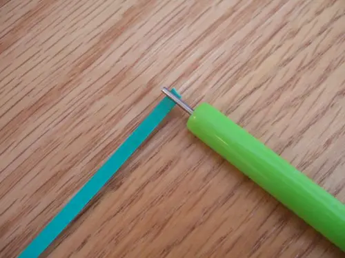1. To make a tight circle, take a quilling wand and a paper strip cut the you desired length. Put the end of the paper strip into the slot on the quilling wand.
